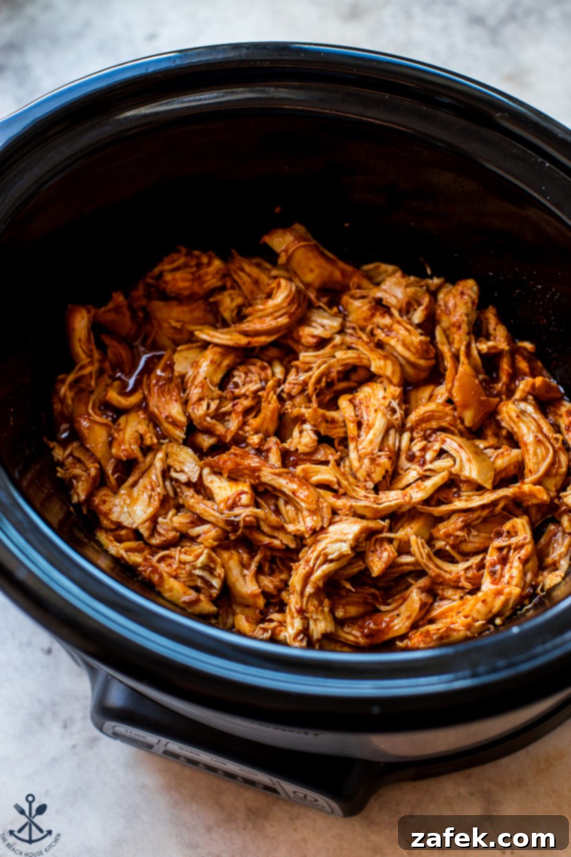 Sticky Slow Cooker Honey Chipotle Chicken 2 Shredded honey chipotle chicken in a slow cooker, garnished with fresh cilantro, ready to be served