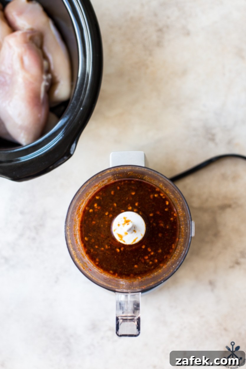 Sticky Slow Cooker Honey Chipotle Chicken 4 Overhead photo of a mini food processor filled with a smooth, reddish-brown chipotle sauce, ready to be poured over chicken