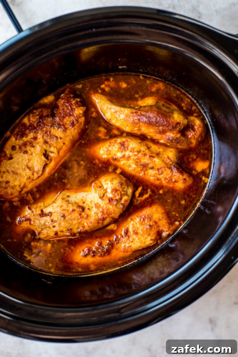 Sticky Slow Cooker Honey Chipotle Chicken 6 Overhead photo of perfectly cooked, whole chicken breasts simmering in a rich, dark honey chipotle sauce within a slow cooker