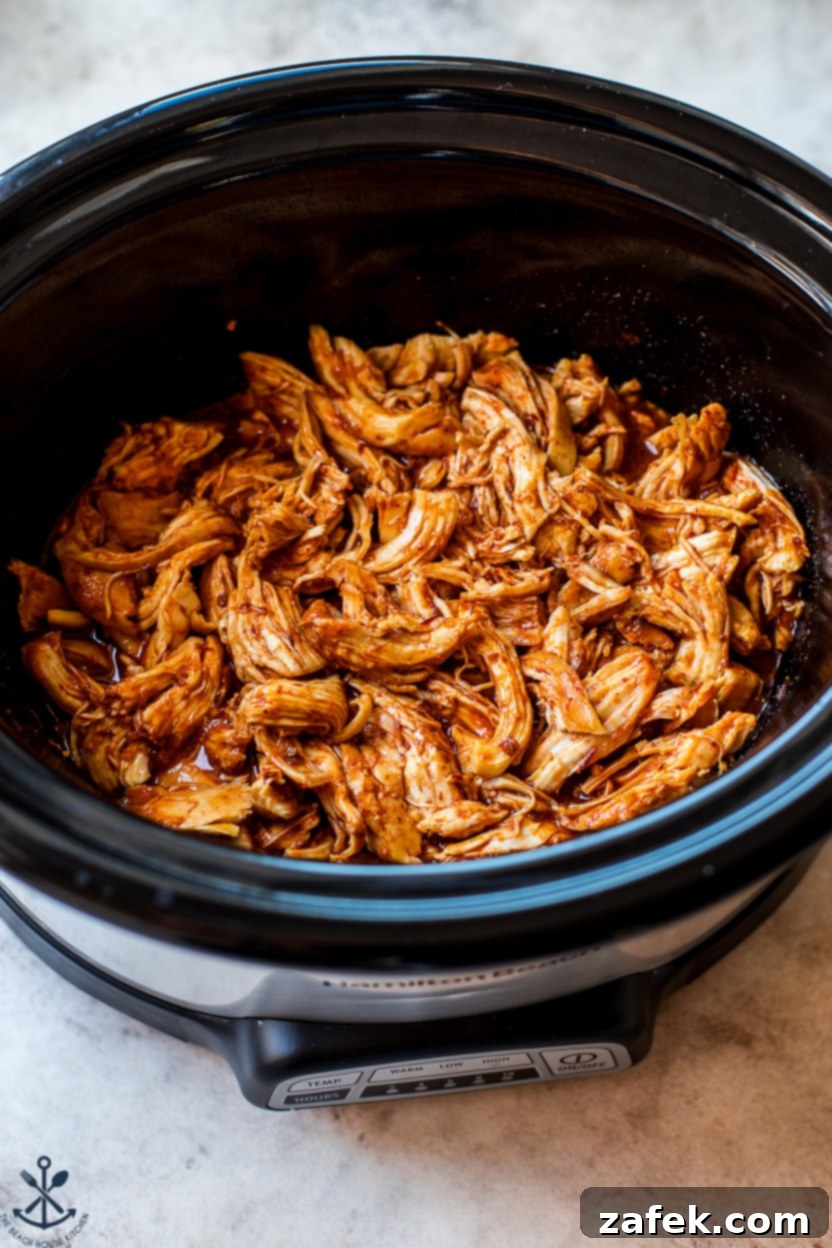 Sticky Slow Cooker Honey Chipotle Chicken 8 Overhead photo of shredded honey chipotle chicken, glistening with sauce, resting in a slow cooker with steam gently rising, highlighting its readiness to be served