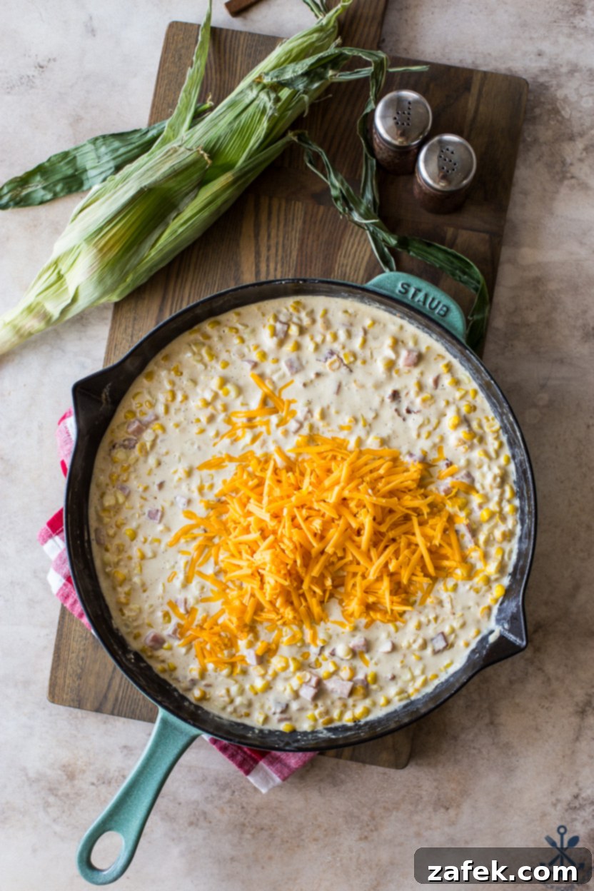 Overhead photo of a skillet of creamy corn topped with shredded yellow cheddar