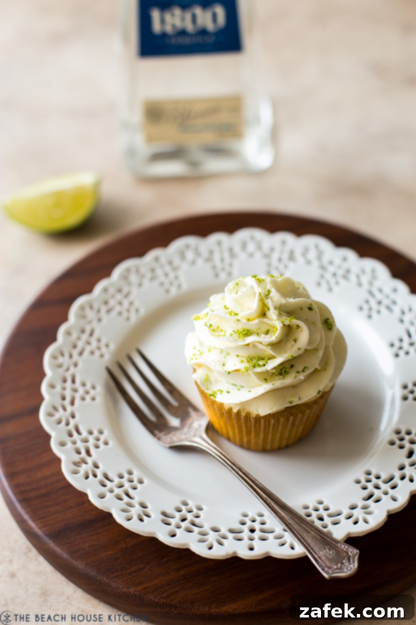 A beautifully frosted Margarita cupcake on a white plate, ready to be enjoyed with a small fork beside it