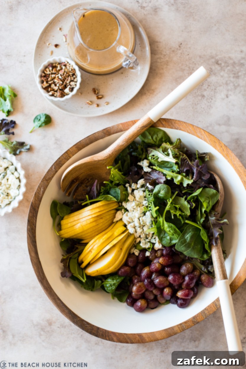 Maple Drizzled Roasted Grape Pear Blue Cheese Salad 7 Overhead photo of a large salad bowl overflowing with mixed greens, sweet roasted grapes, perfectly sliced pears, and crumbles of blue cheese, showcasing the bountiful and colorful fall salad.