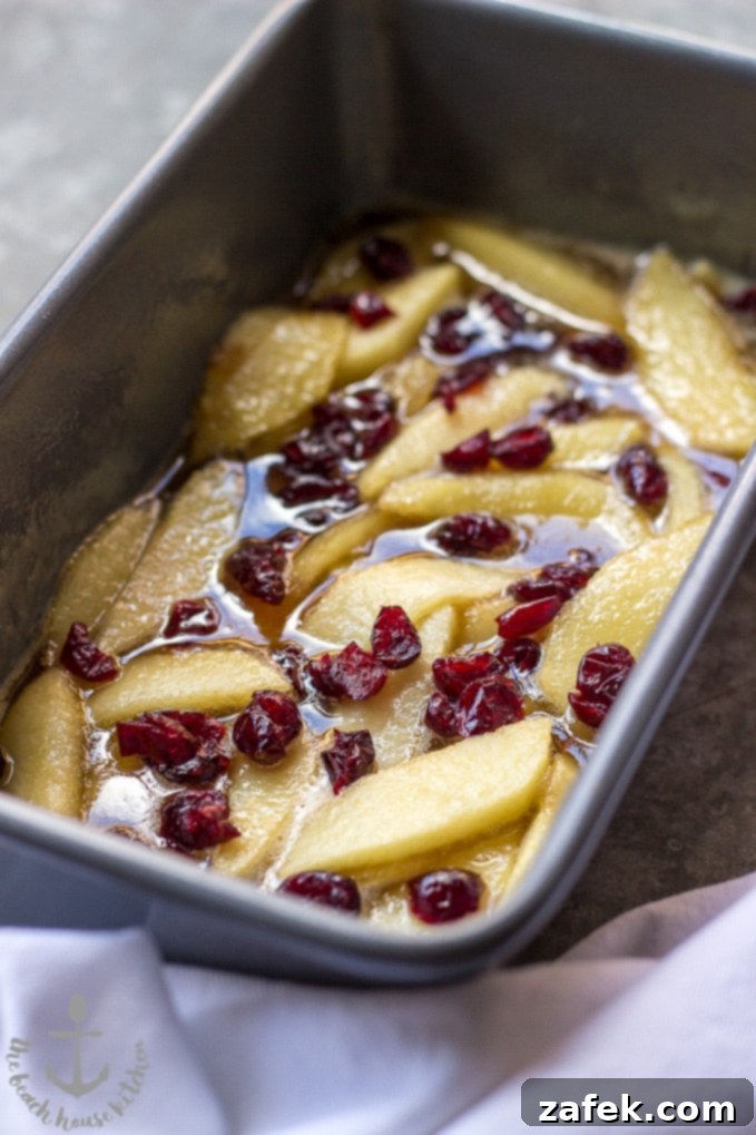 Sticky Caramel Apple Cranberry Upside-Down Loaf 6 Caramelized Apple Cranberry Upside Down Bread on a cutting board, ready to be sliced.