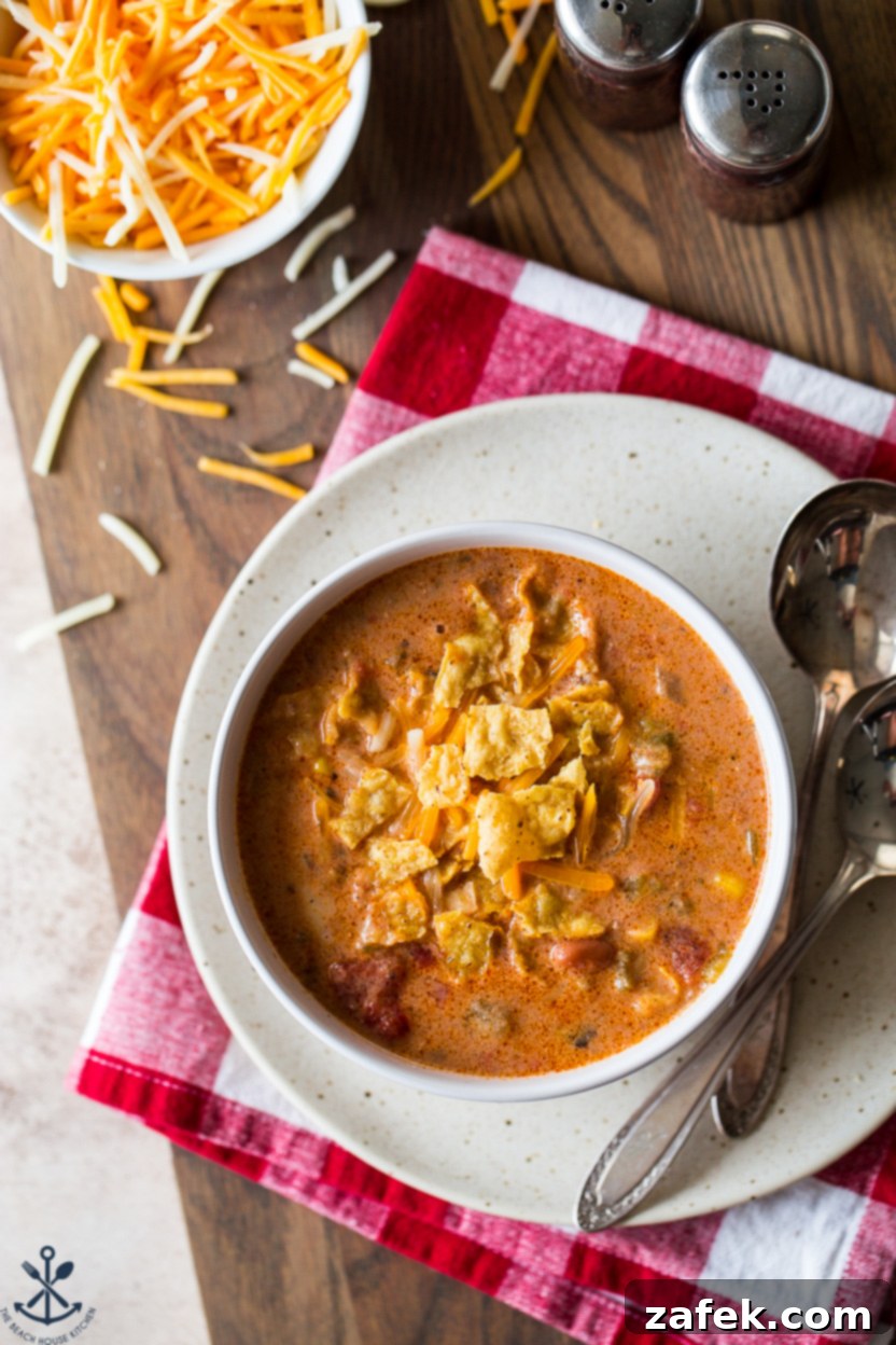 Up close overhead photo of a bowl of beef enchilada soup topped with crushed tortilla chips