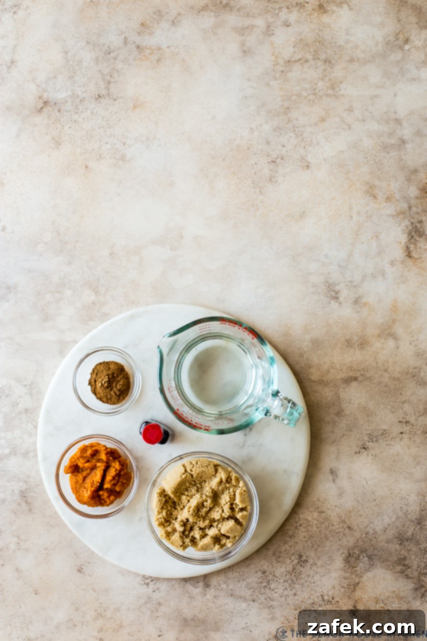Fireside Pumpkin Old Fashioned 4 An overhead shot showcasing the fresh ingredients for homemade pumpkin spice syrup laid out on a round marble board, ready for preparation.