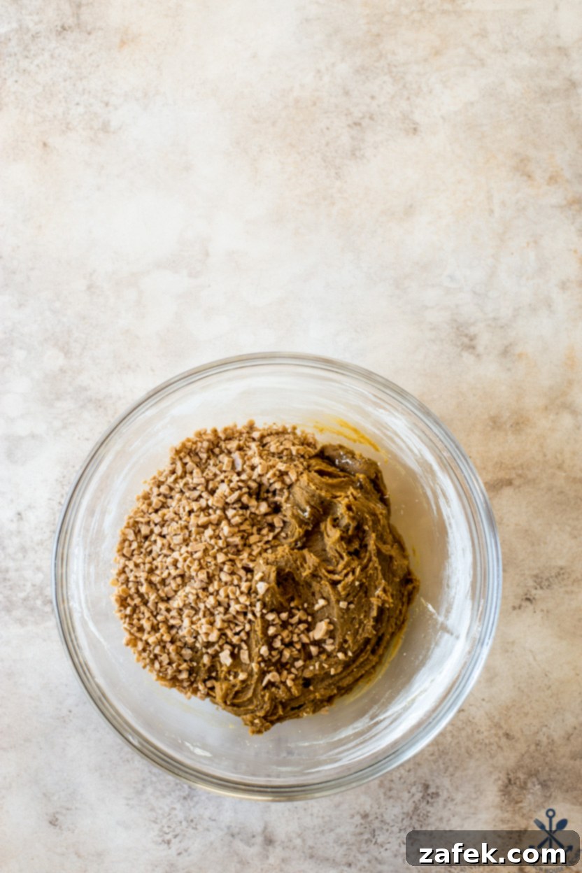 Overhead photo of a glass bowl of cookie dough topped with toffee bits