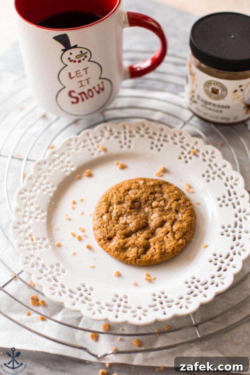 An espresso toffee cookie on a white plate with a lace-like edging