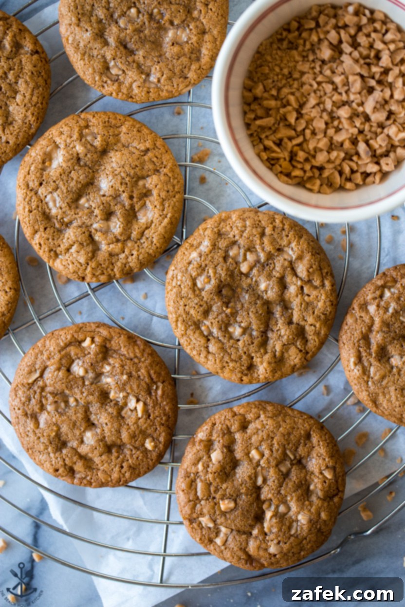 Overhead photo of toffee cookies on a wire rack with a small bowl of toffee bits