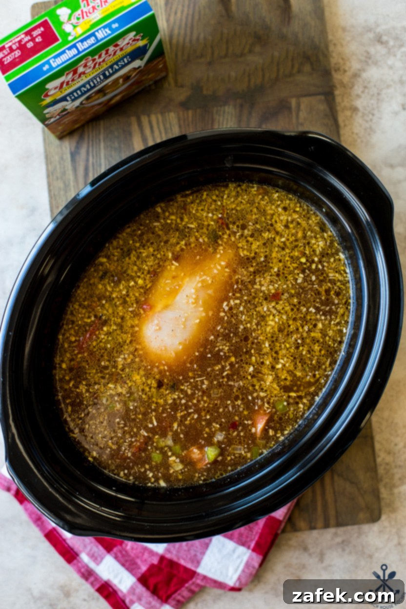 Overhead photo of a slow cooker filled with a gumbo base and chicken