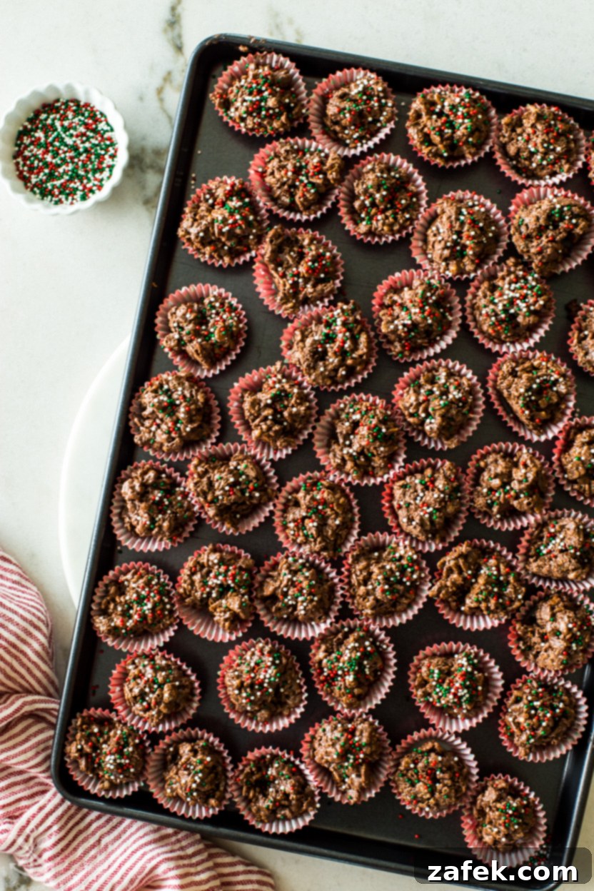 Overhead photo of a baking sheet filled with rows of perfectly formed and set crispy chocolate coconut crunch cups, topped with colorful sprinkles, ready for serving or packaging