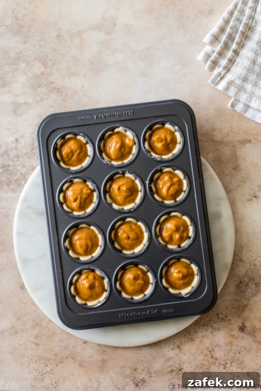 Overhead photo of pre-baked small pumpkin pies in a muffin tin