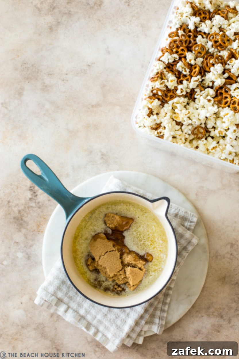 Gourmet Gingerbread Caramel Pretzel Popcorn 5 Overhead photo of a pot filled with butter and brown sugar with a container of popcorn and pretzels off to the side,