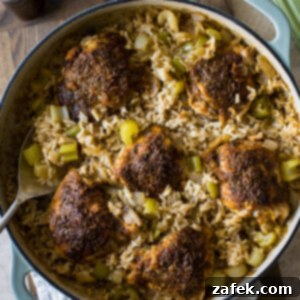 A Taste of Home: Mum's Chicken and Rice 9 Close-up photo of a portion of Mum's Chicken and Rice in a skillet, showcasing the crispy skin of the chicken thigh and the fluffy, herb-infused basmati rice underneath.