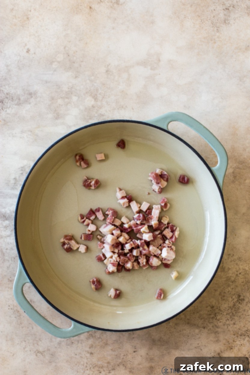 Overhead photo of a skillet of chopped pancetta, rendering in olive oil.