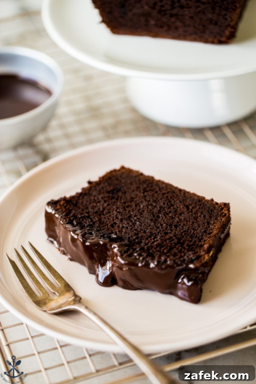 Decadent Chocolate Loaf 8 Up close photo of a slice of chocolate cake on a pink plate with a fork