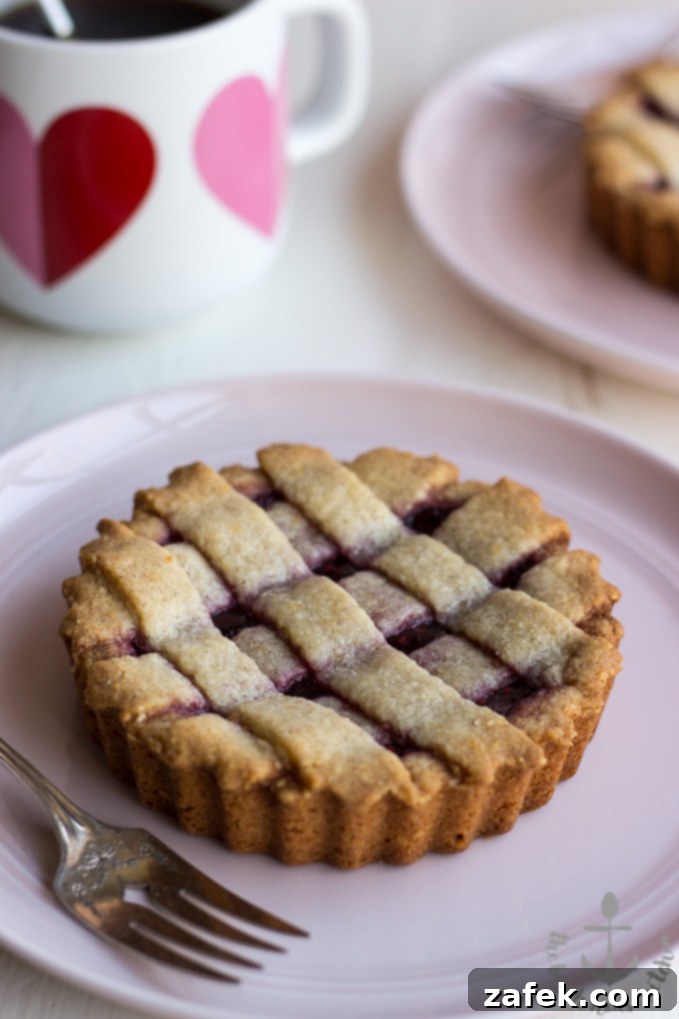 A close-up of a single Miniature Linzer Torte with raspberry jam glistening.