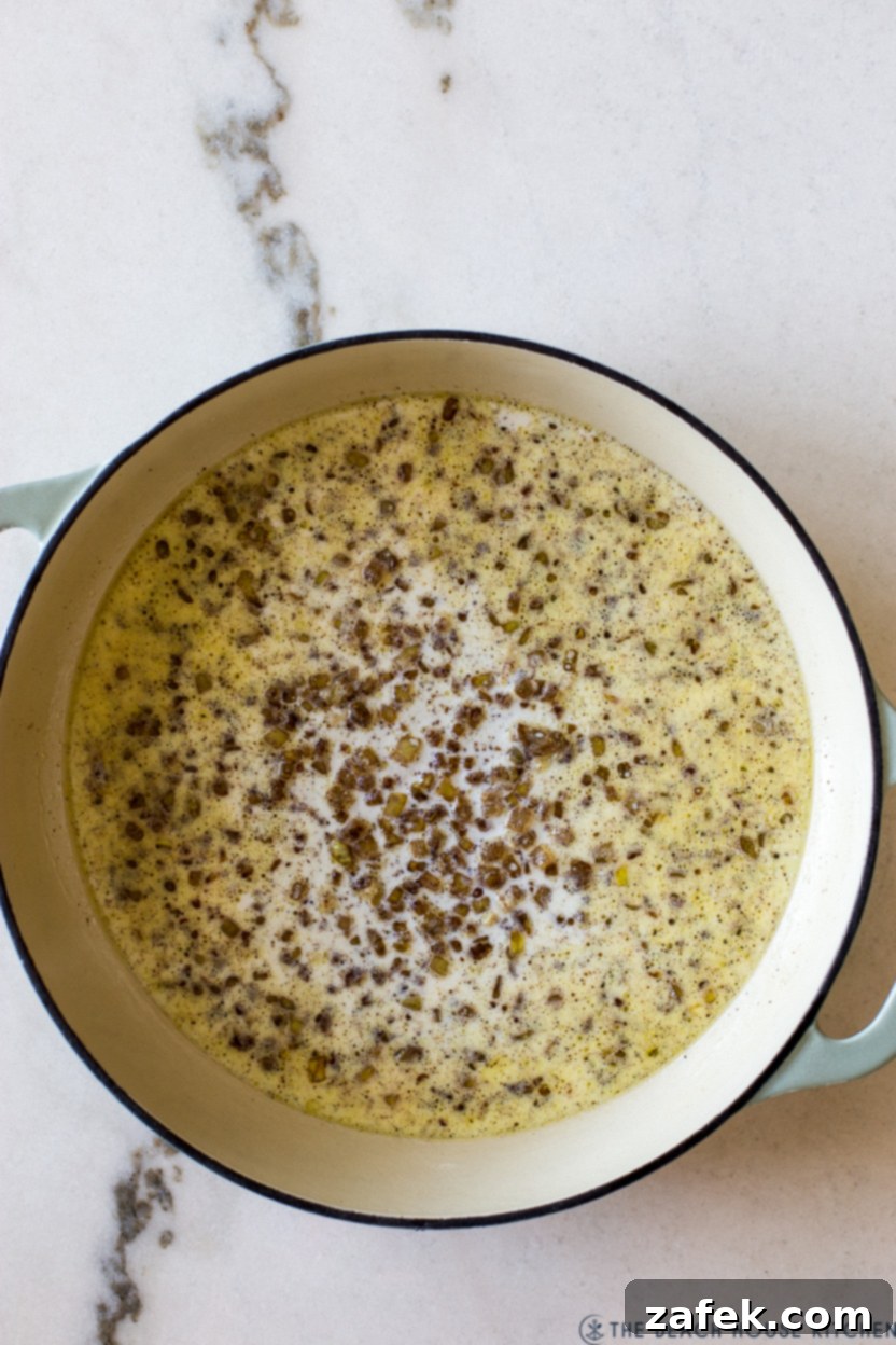 Overhead photo of a skillet with cooked onions and milk simmering, ready for the breadcrumbs