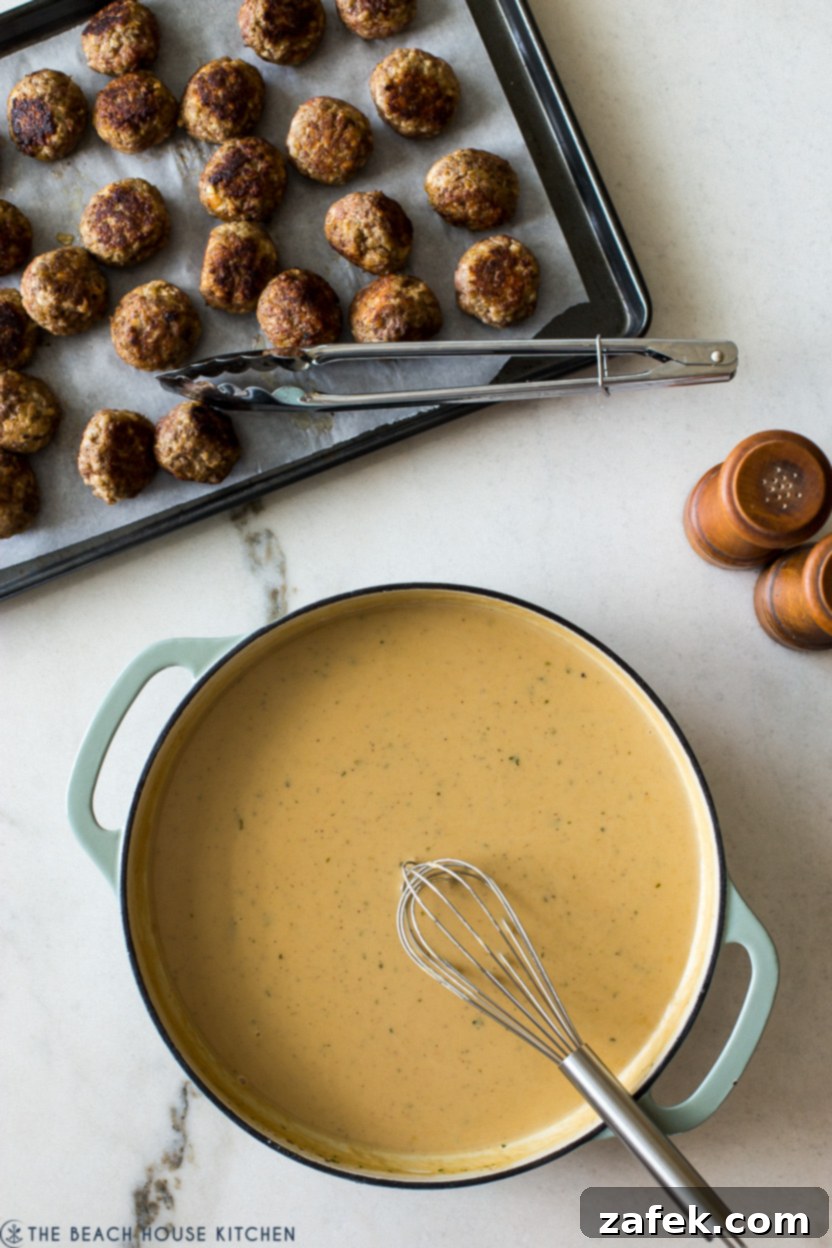 Overhead photo of a skillet with rich Swedish Meatball gravy next to a tray of browned meatballs