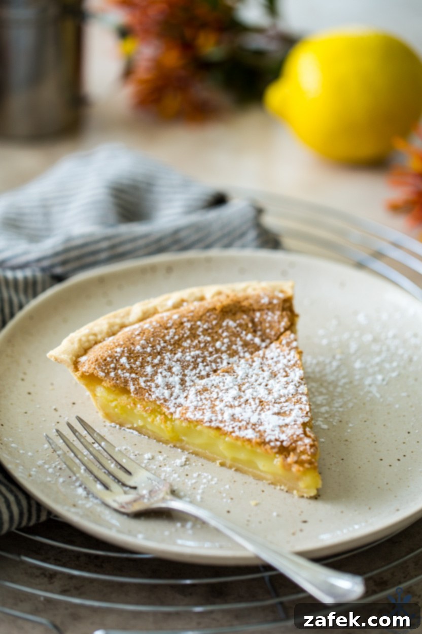 Tangy Lemon Chess Pie 3 A perfectly sliced piece of Lemon Chess Pie on a white plate, served with a fork, showing its smooth, golden filling.