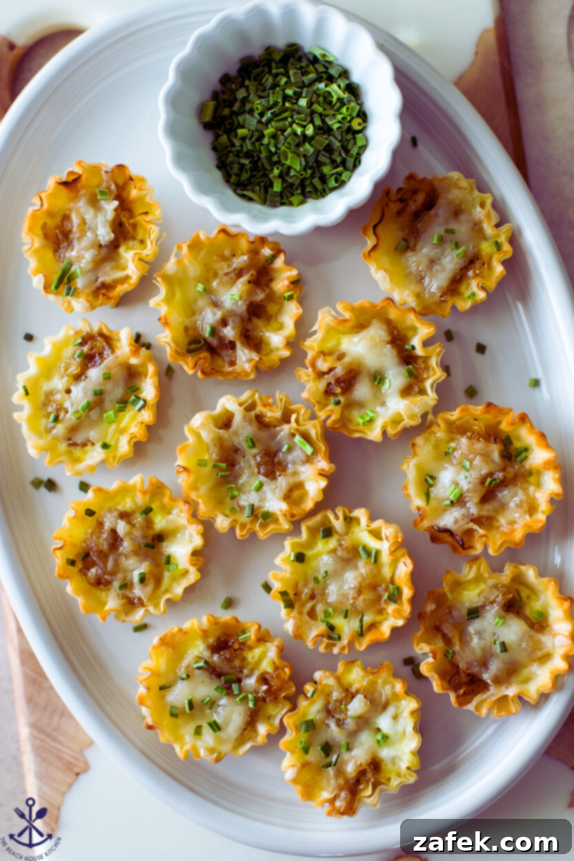 Up close overhead photo of French Onion Soup Bites on an oval platter, showing melted cheese and golden pastry