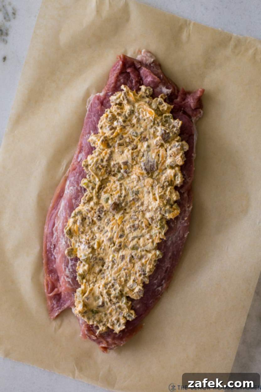 Exquisite Bacon-Wrapped Stuffed Pork Tenderloin 6 Overhead photo of a pre-baked stuffed pork tenderloin, neatly rolled and ready for the oven