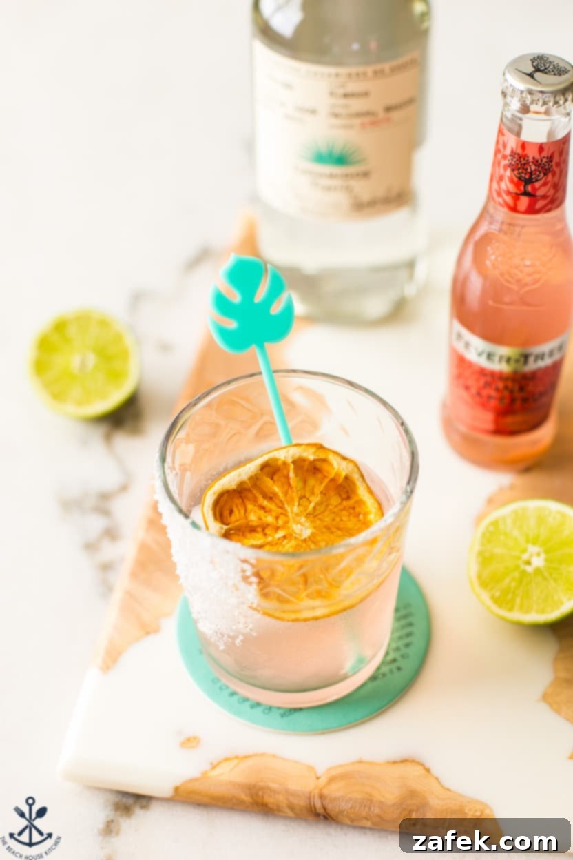 The Perfect Paloma Cocktail 3 Overhead photo of a Paloma cocktail topped with a dehydrated orange in the glass, with condensation on the glass.