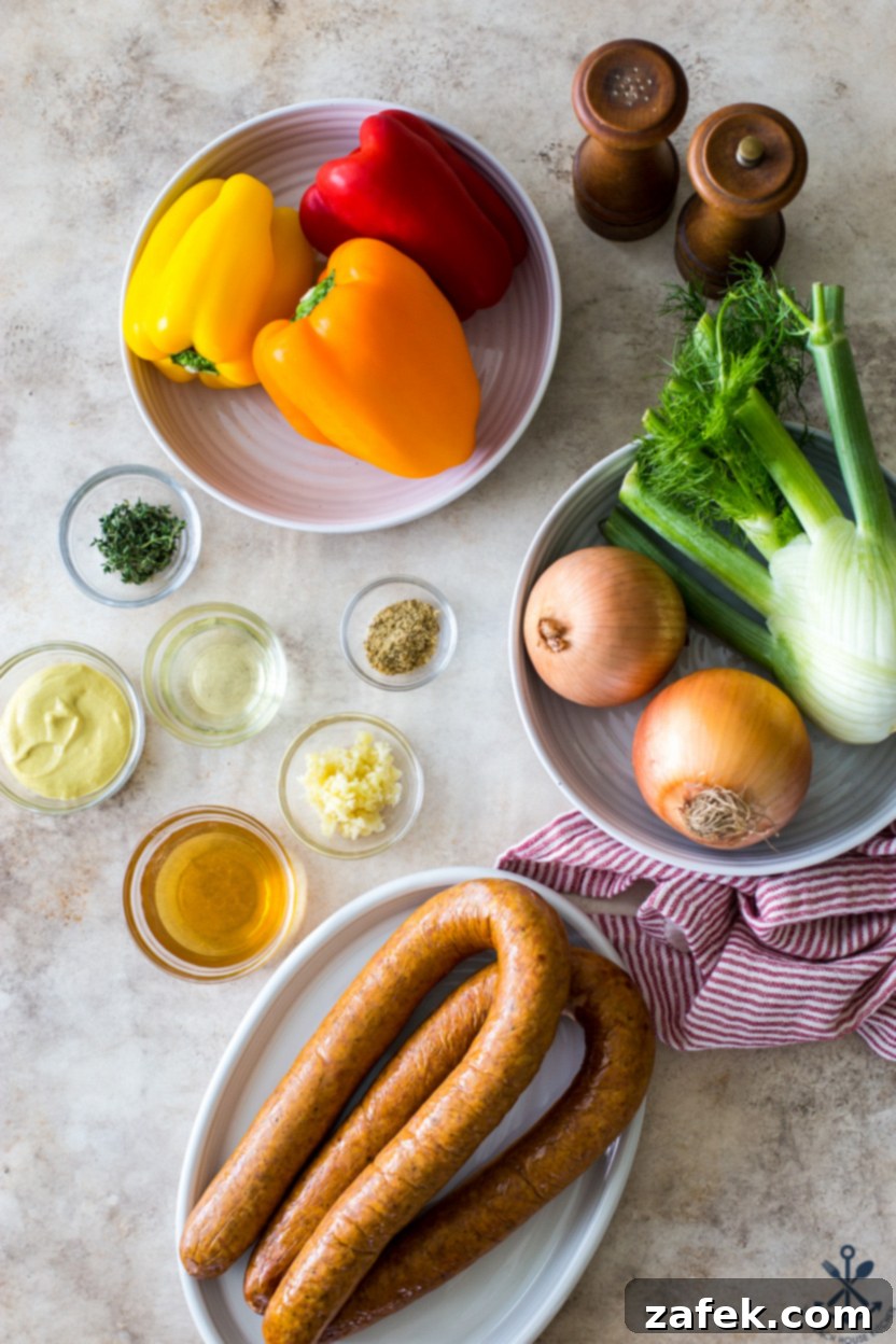 An organized overhead shot of all the fresh, prepped ingredients, including vibrant bell peppers, sliced onions, and a fennel bulb, laid out for a Hasselback Kielbasa sheet pan meal.