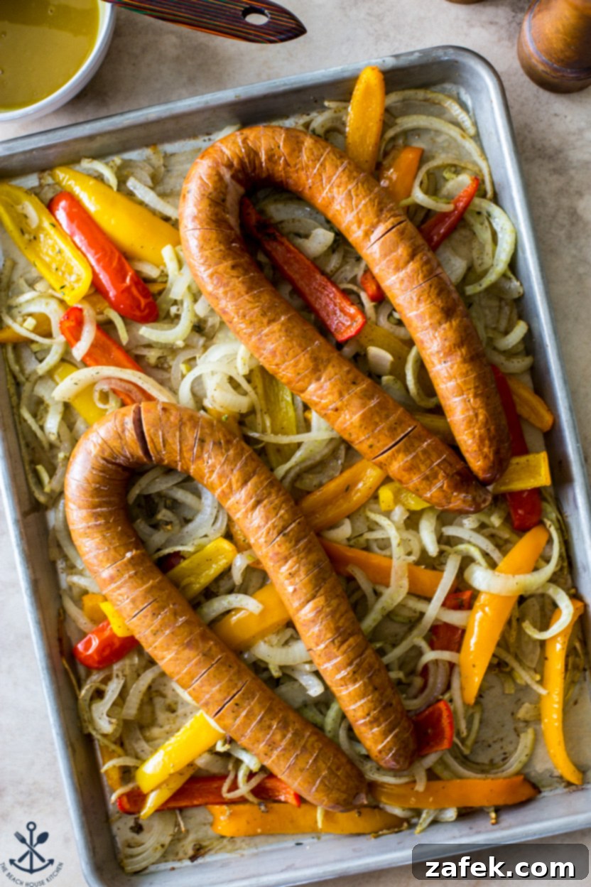 A close-up, tempting overhead photo of the finished sheet pan meal, highlighting the perfectly crispy Hasselback kielbasa and tender, caramelized roasted vegetables, ready to be enjoyed.