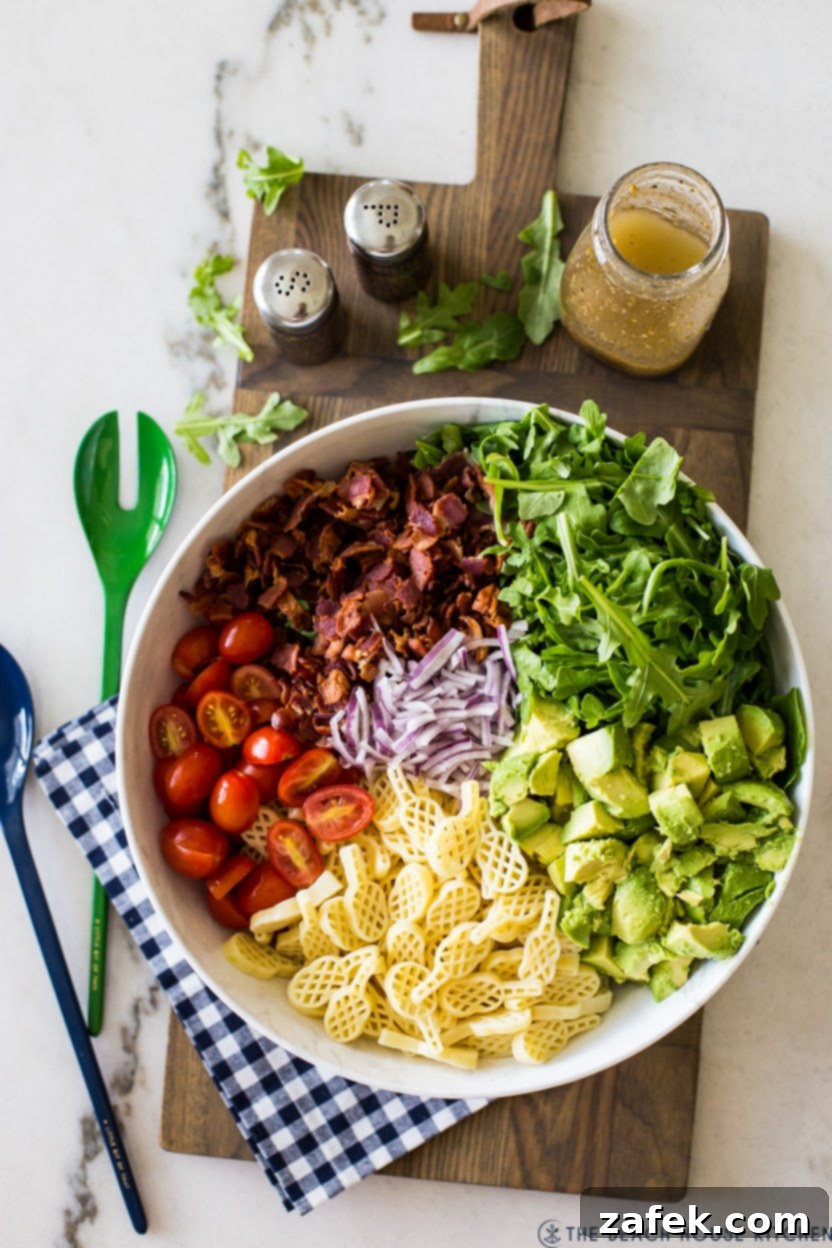 The Ultimate BLT Avocado Pasta Salad 6 Overhead photo of a pre-tossed BLT pasta salad with all ingredients layered before mixing