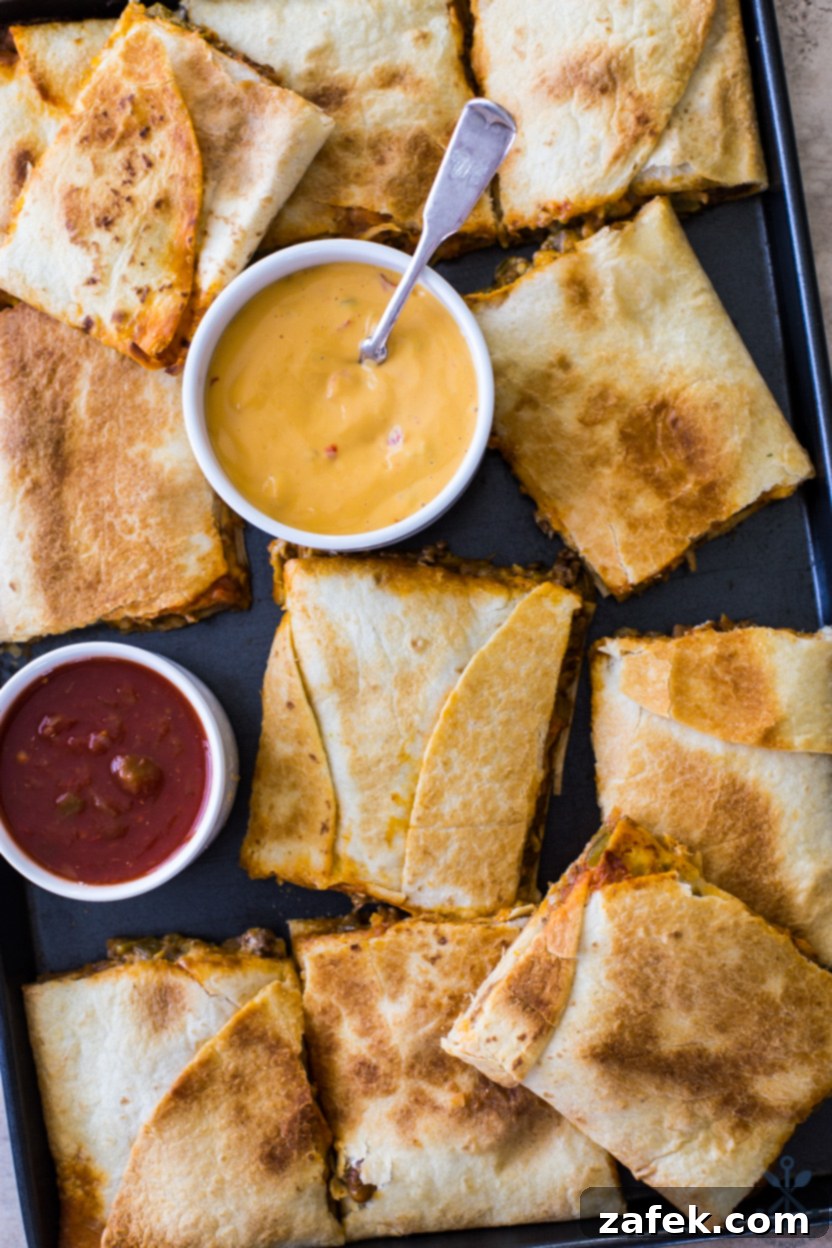 Up close overhead photo of crispy, golden sheet pan beef quesadillas with visible melted cheese and savory filling