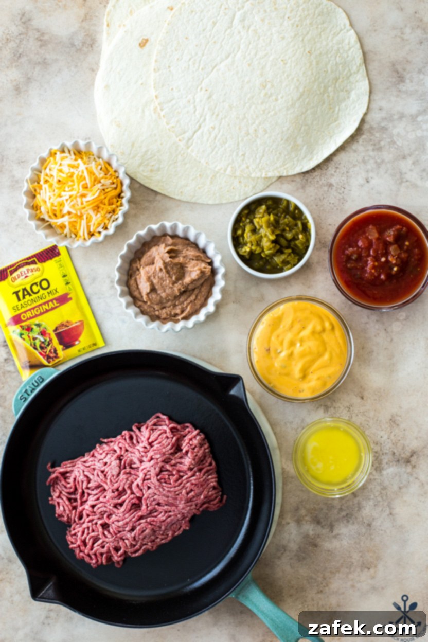 Overhead photo of an organized display of fresh ingredients for beef sheet pan quesadillas, including ground beef, spices, various cheeses, stack of tortillas, and colorful toppings