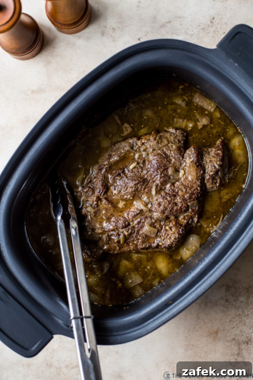 Overhead photo of cooked beef in a slow cooker, ready to be served
