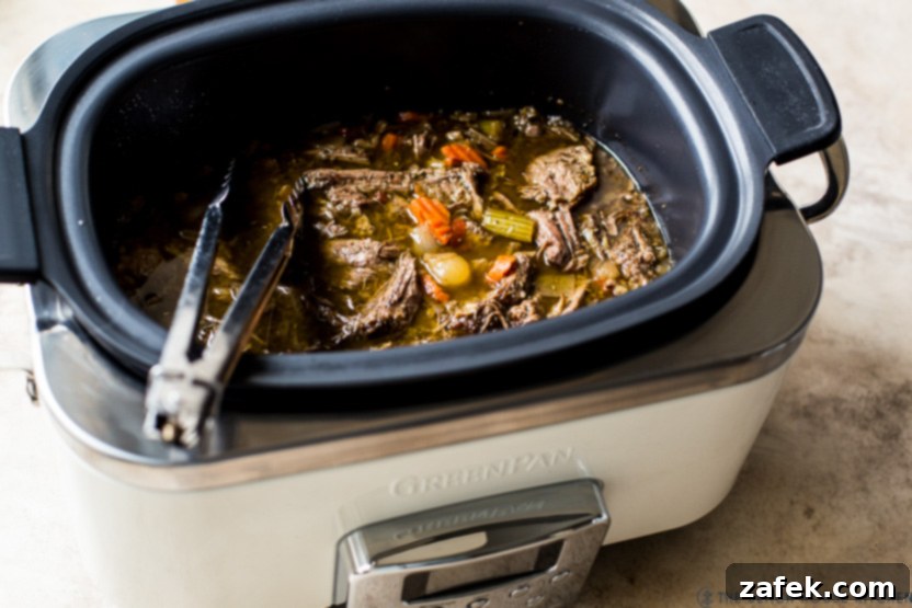 Italian beef in a slow cooker, served with a side of bread and ready to eat