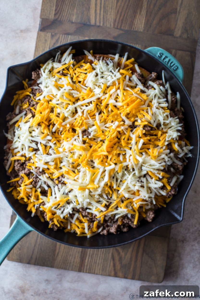 Southwest Tamale Bake 10 Pre-baked tamale pie in a skillet, covered with a layer of un-melted cheese, ready for the final bake