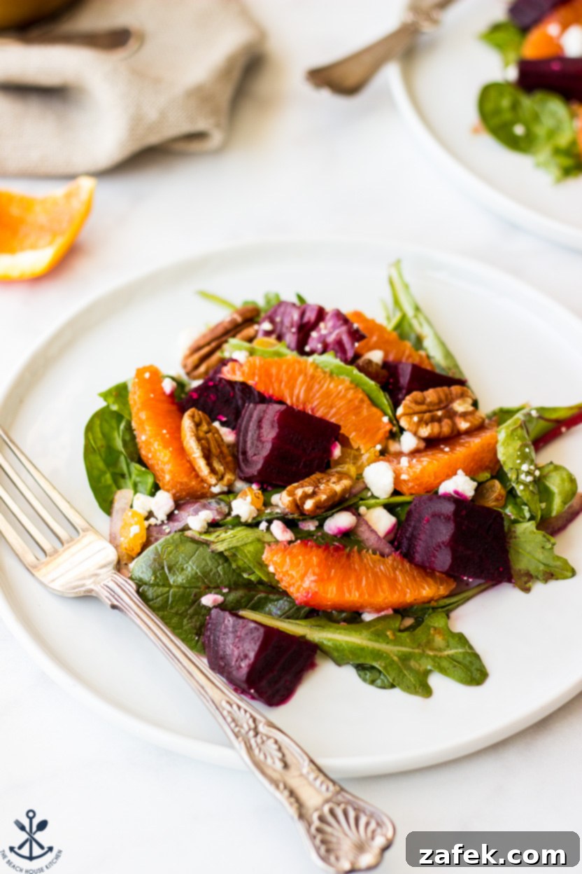Vibrant Beet and Orange Salad 4 Up close photo of a salad with greens, beets, oranges, nuts and feta crumbles