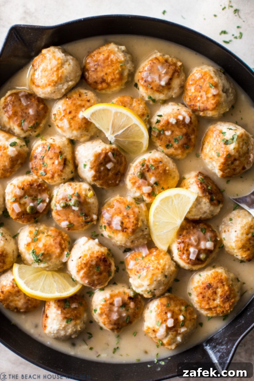 Close-up shot of golden-brown chicken piccata meatballs in a skillet, ready to be coated in sauce.