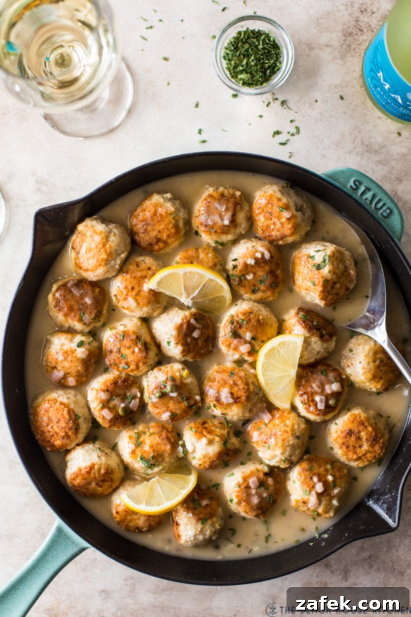 A close-up of a single chicken piccata meatball on a fork, showcasing its tender texture and rich sauce.