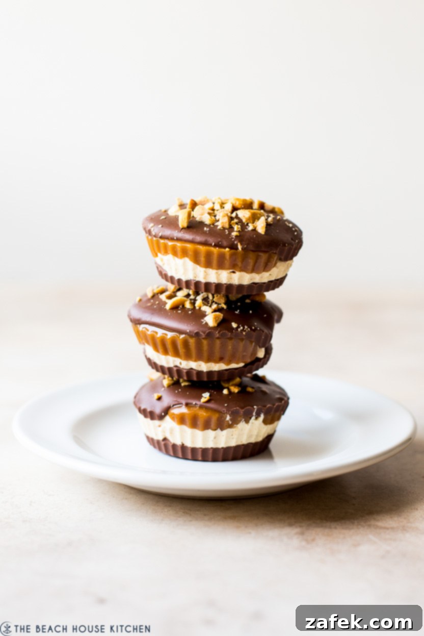 Caramel Peanut Chocolate Dream Cups 2 A stack of three homemade Snickers cups on a white plate, showcasing the distinct layers of chocolate, peanut nougat, and caramel.