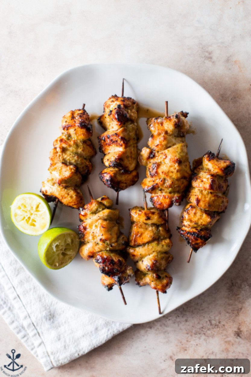 Zesty Sweet Heat Air Fryer Chicken Skewers 2 Overhead photo of a plate of chicken skewers with two lime halves and fresh herbs