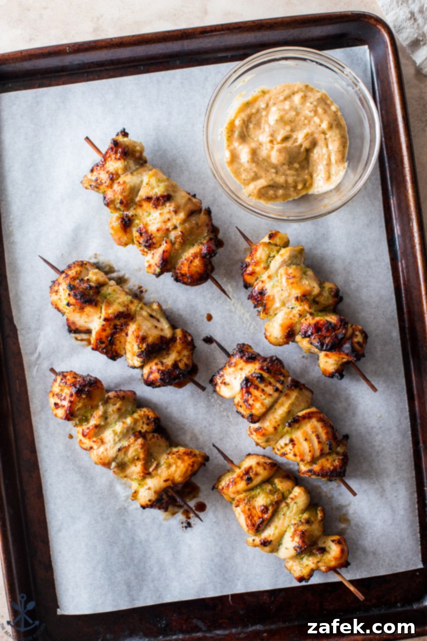 Zesty Sweet Heat Air Fryer Chicken Skewers 7 Overhead photo of six perfectly cooked honey jalapeno lime chicken skewers on a plate, with a small bowl of the delicious butter glaze