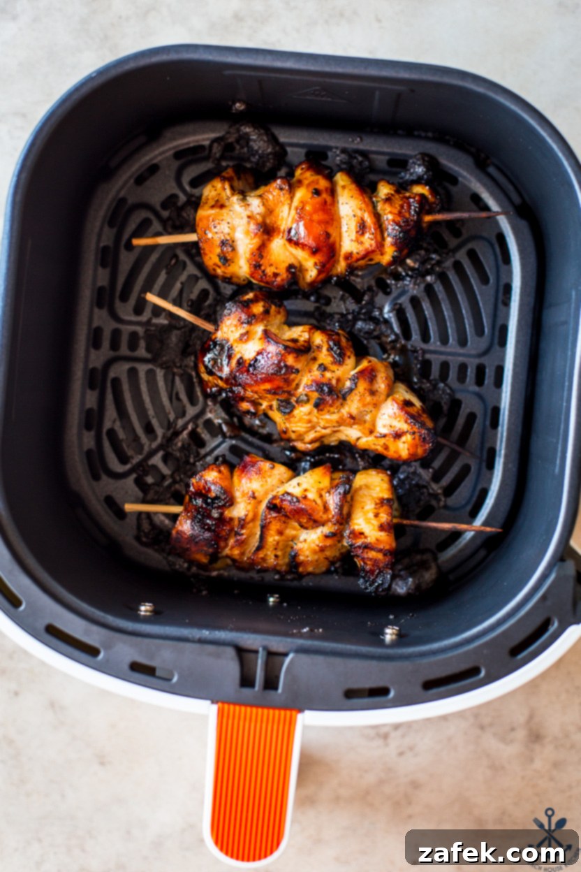 Zesty Sweet Heat Air Fryer Chicken Skewers 8 Overhead photo of three sizzling chicken skewers cooking in an air fryer basket