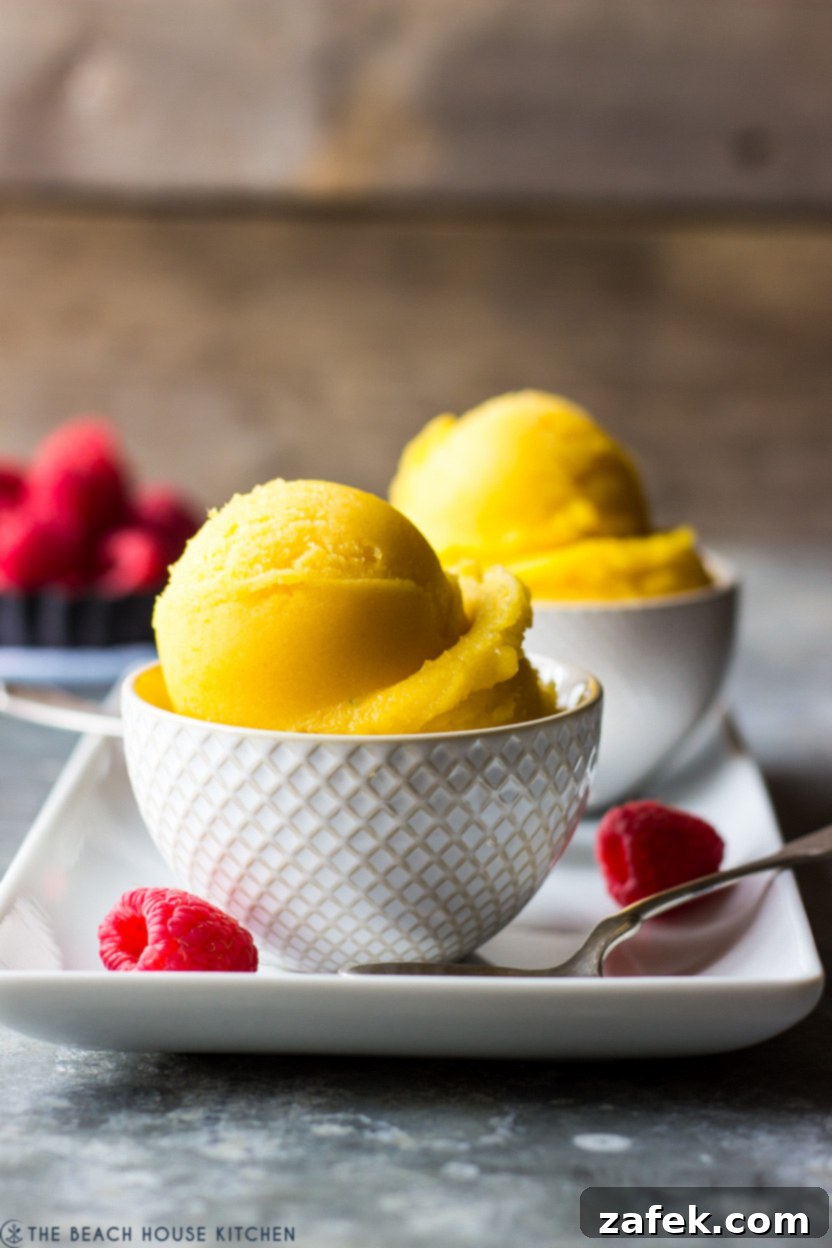 A small white bowl overflowing with vibrant, golden mango sorbet, ready to be enjoyed.