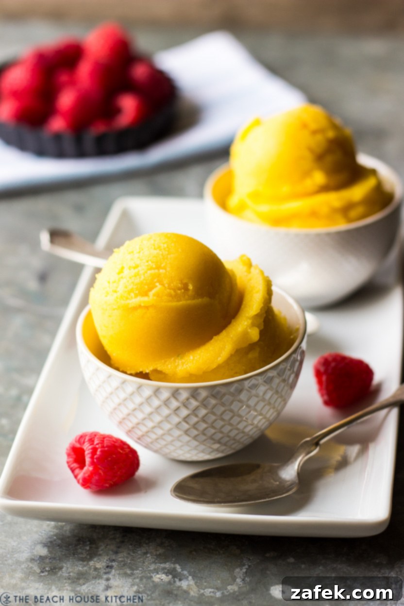 A close-up view of mango sorbet in a white bowl, showing its smooth, creamy texture and vibrant color.