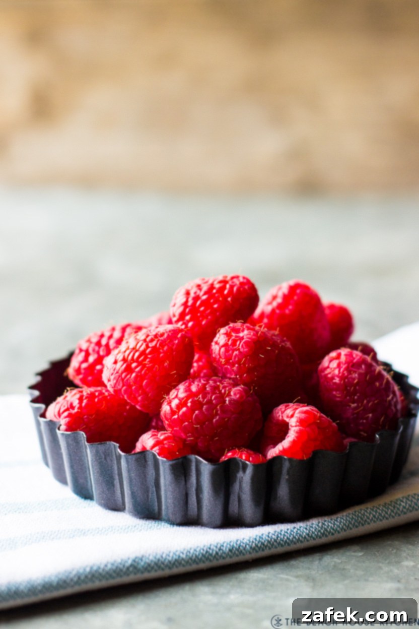 A small tart pan filled with a colorful array of fresh, vibrant raspberries, perfect for garnish.
