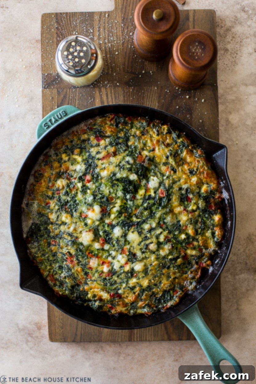 Overhead photo of a baked spinach egg bake in a skillet, showcasing its golden-brown top.