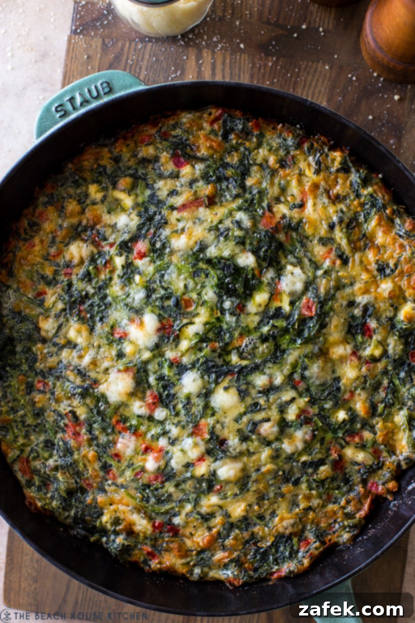 Up close overhead photo of a freshly baked Cheesy Greek Spinach Egg Bake, golden and bubbly.