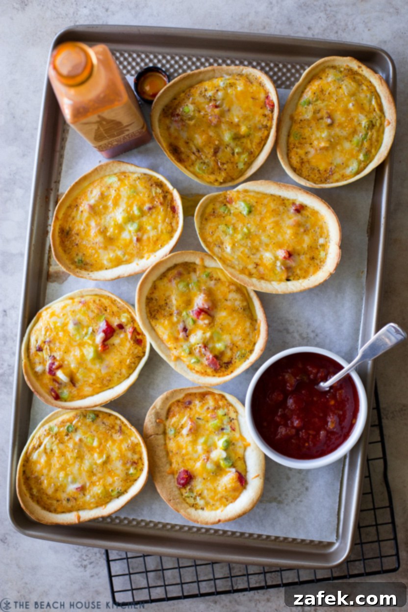Loaded Mexican Quiche Boats 2 Overhead photo of 8 Mexican taco boat quiches on a baking sheet, golden and inviting