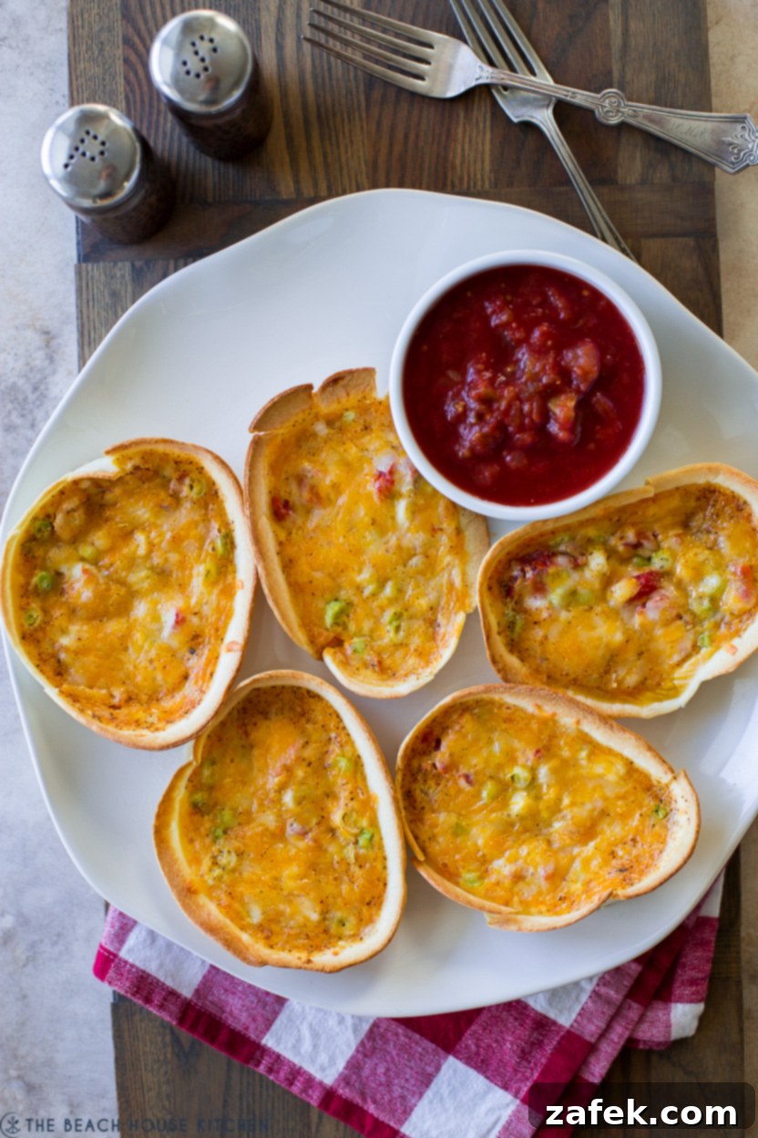 Loaded Mexican Quiche Boats 3 Overhead photo of 5 taco boat quiches on a white plate with a bowl of salsa, garnished with cilantro