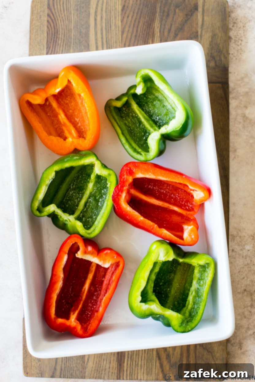 Savory Stuffed Peppers 7 Overhead photo of vibrant, cleaned, and halved bell peppers arranged in a white baking dish, ready for stuffing
